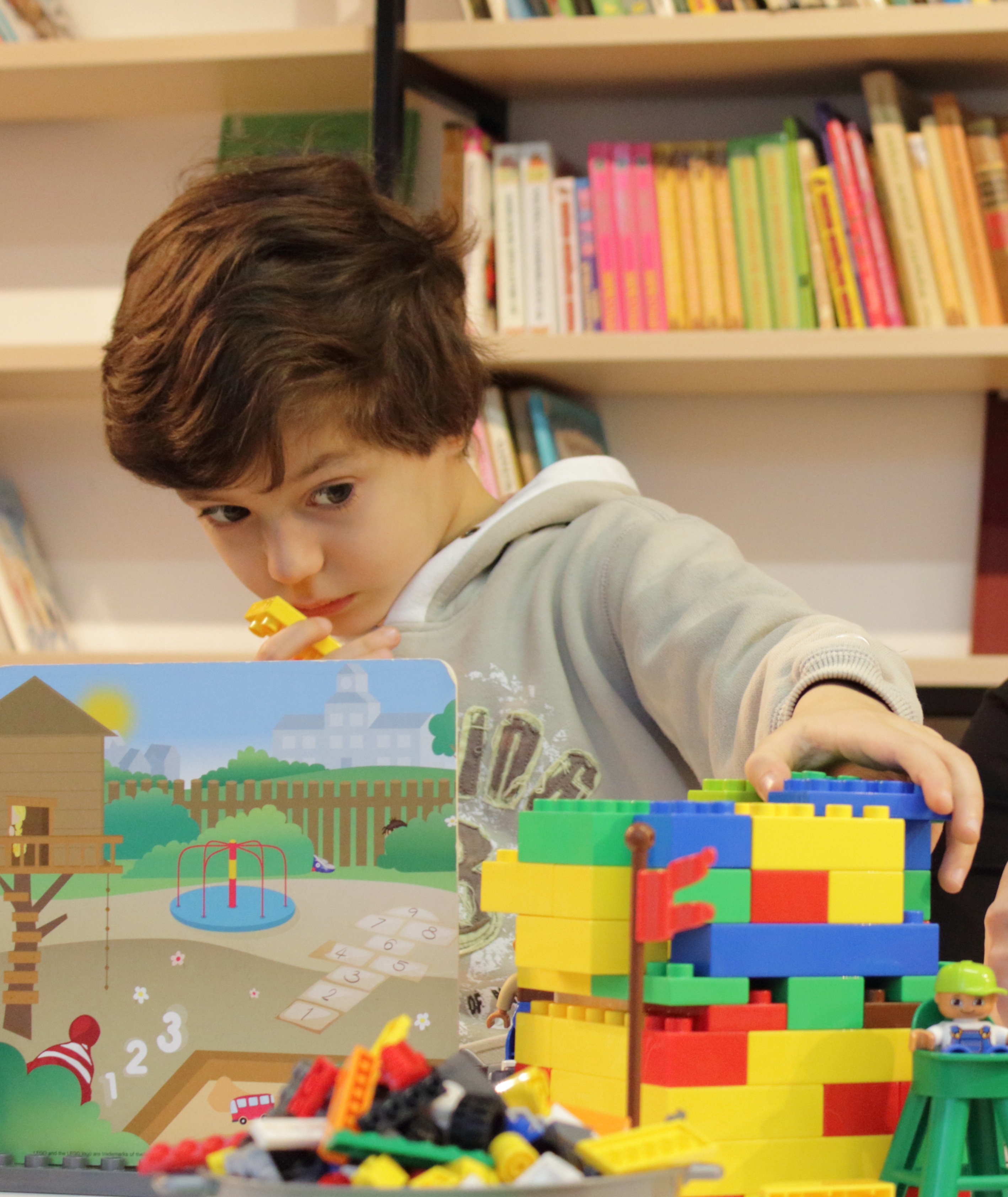colourful image of little boy looking intriqued while figuring out his lego project