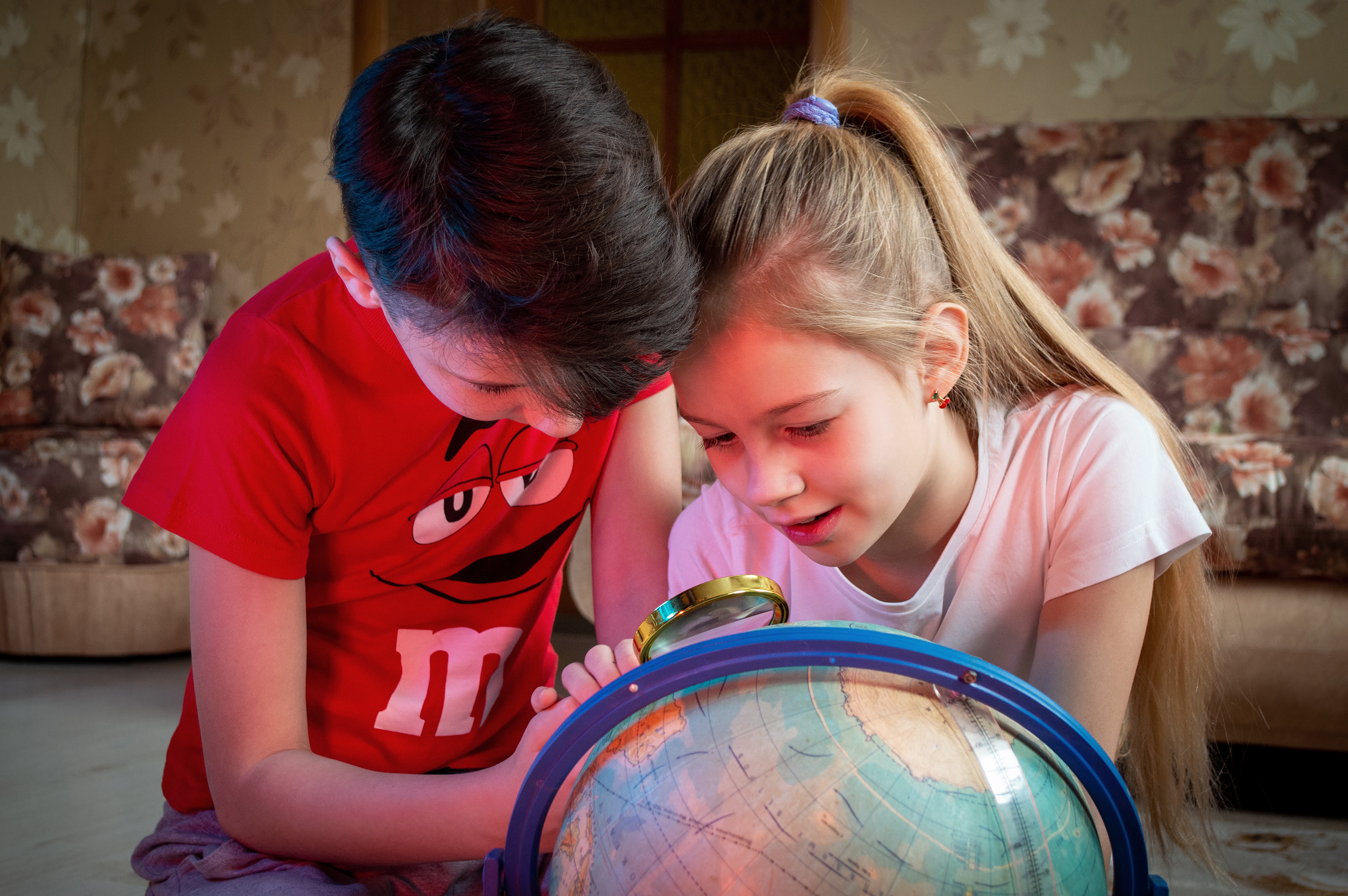 children excited to learn, looking at a globe atlas