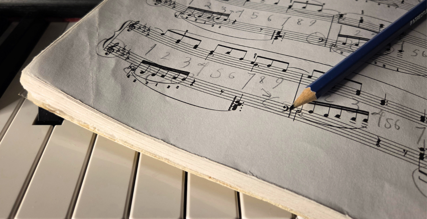 marked piano sheet music with the tipe of a pencil showing